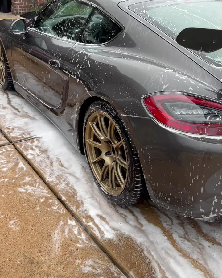 Porsche Cayman with bronze wheels being foamed in a driveway